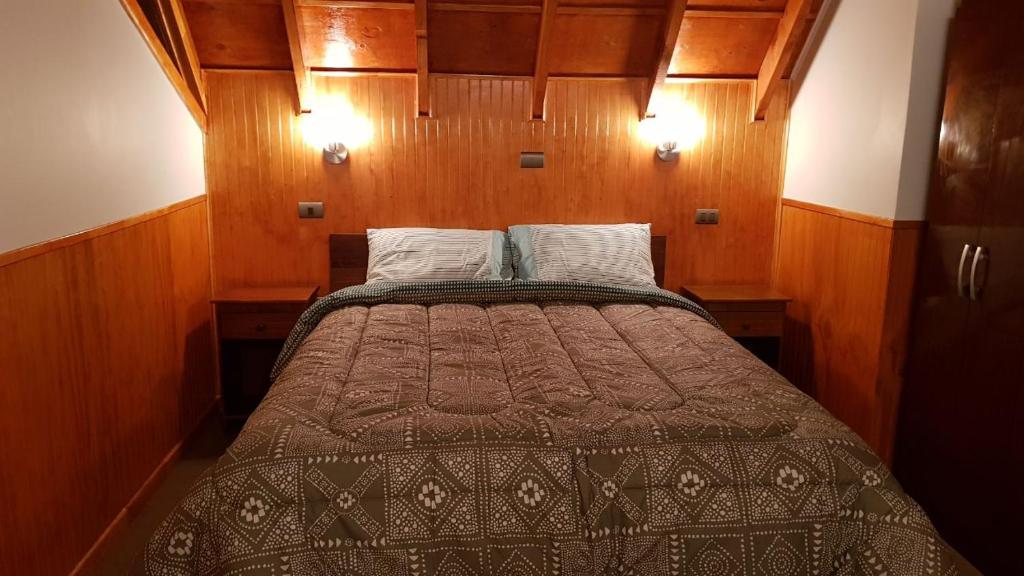 a bed in a small room with wooden walls at Cabañas Rayen in Río Bueno