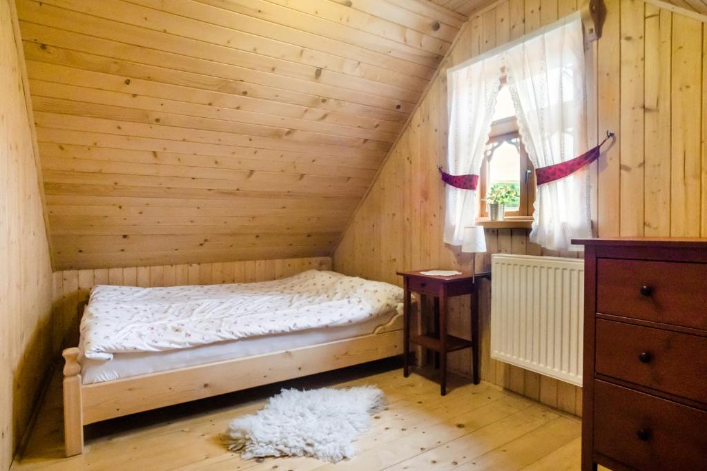 ein Schlafzimmer mit einem Bett in einem Holzzimmer in der Unterkunft Pienińskie Herbarium zdrowie i dobre samopoczucie in Grywałd