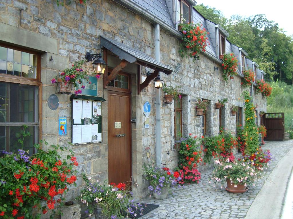 un bâtiment en pierre avec des fleurs sur son côté dans l'établissement La Clochette, à Celles