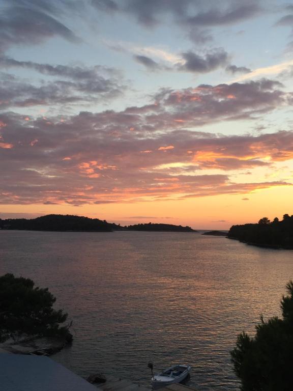 a boat sitting on the water at sunset at Apartments Pomeštak in Pomena