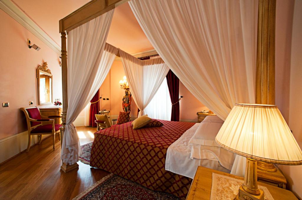a bedroom with a canopy bed and a table with a lamp at Albergo La Lanterna in Sarteano