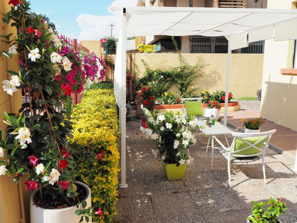 um pátio com flores e um guarda-sol branco e cadeiras em Residence Hotel Vittoria em Tirrenia
