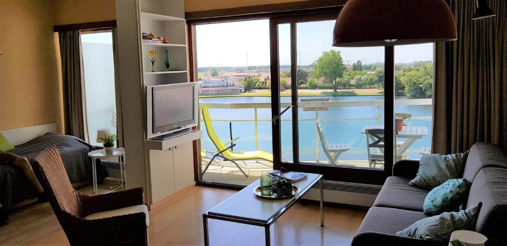 een woonkamer met een bank, een televisie en een balkon bij Duinbergen Laguna Beach in Knokke-Heist