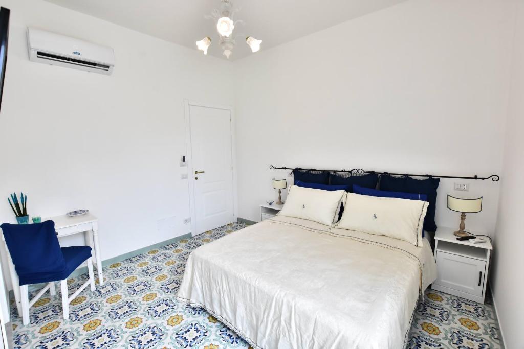 Un dormitorio con una cama blanca y una silla azul. en Il Gelsomino Amalfi, en Amalfi