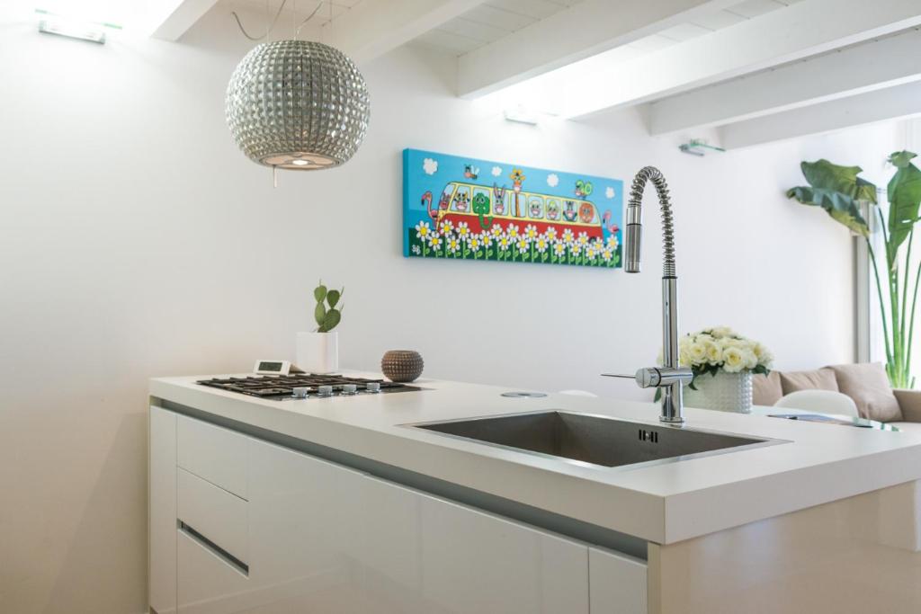 una cucina bianca con lavandino e piano cottura di A modo nostro Design Home a Cagliari