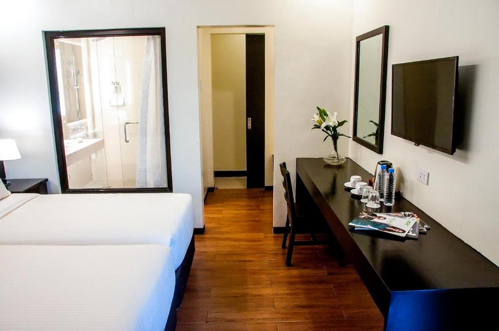 a bedroom with a bed and a desk with a mirror at Piña Suites in Ormoc