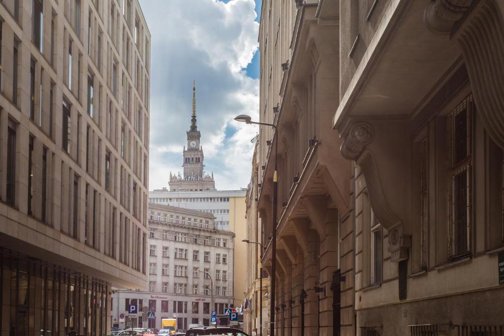 une rue de la ville avec de grands bâtiments et une tour de l'horloge dans l'établissement Latte Apartment, à Varsovie