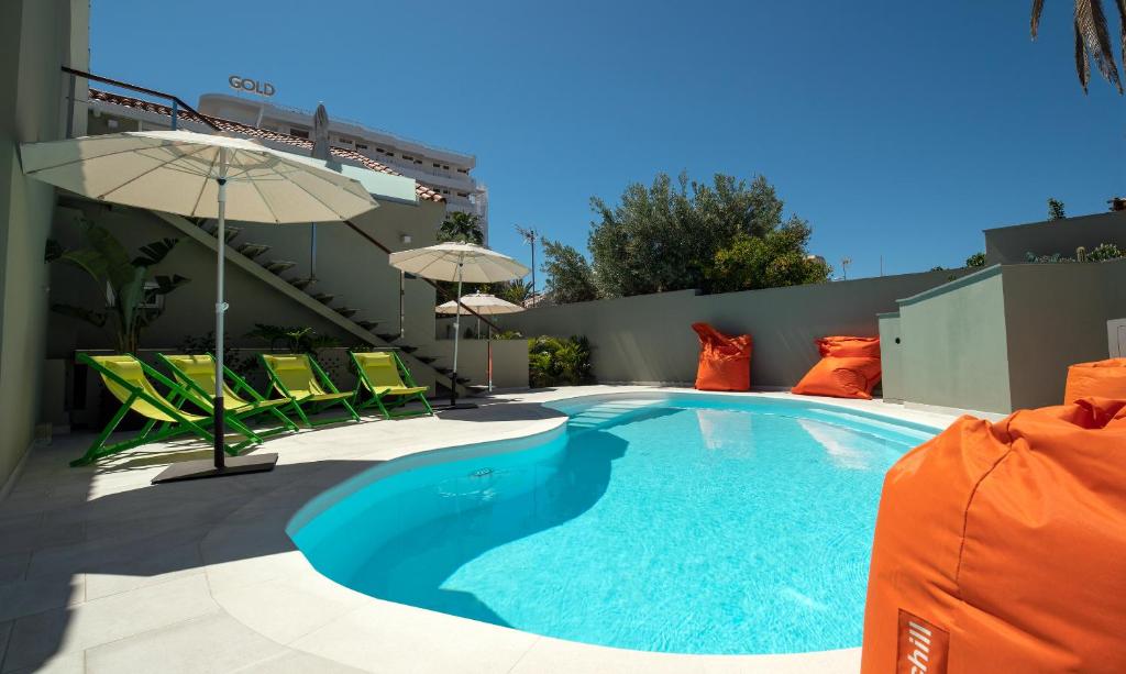 普拉亞戴爾雷安格萊斯的住宿－Villa RG Boutique Hotel - Adults Only，一个带椅子和遮阳伞的游泳池