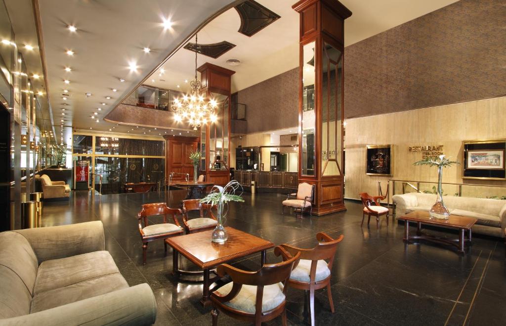 a lobby with a couch and tables and chairs at Hotel Presidente Buenos Aires in Buenos Aires