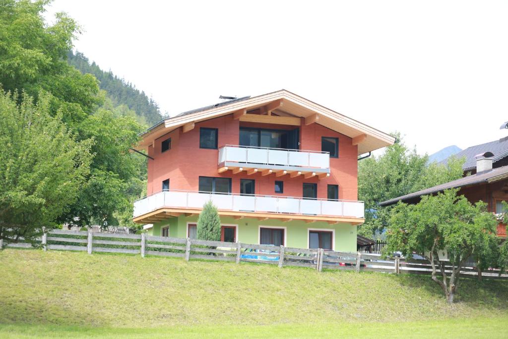 une maison sur une colline avec une clôture devant elle dans l'établissement Ferienwohnung Josef Pötscher, à Matrei in Osttirol