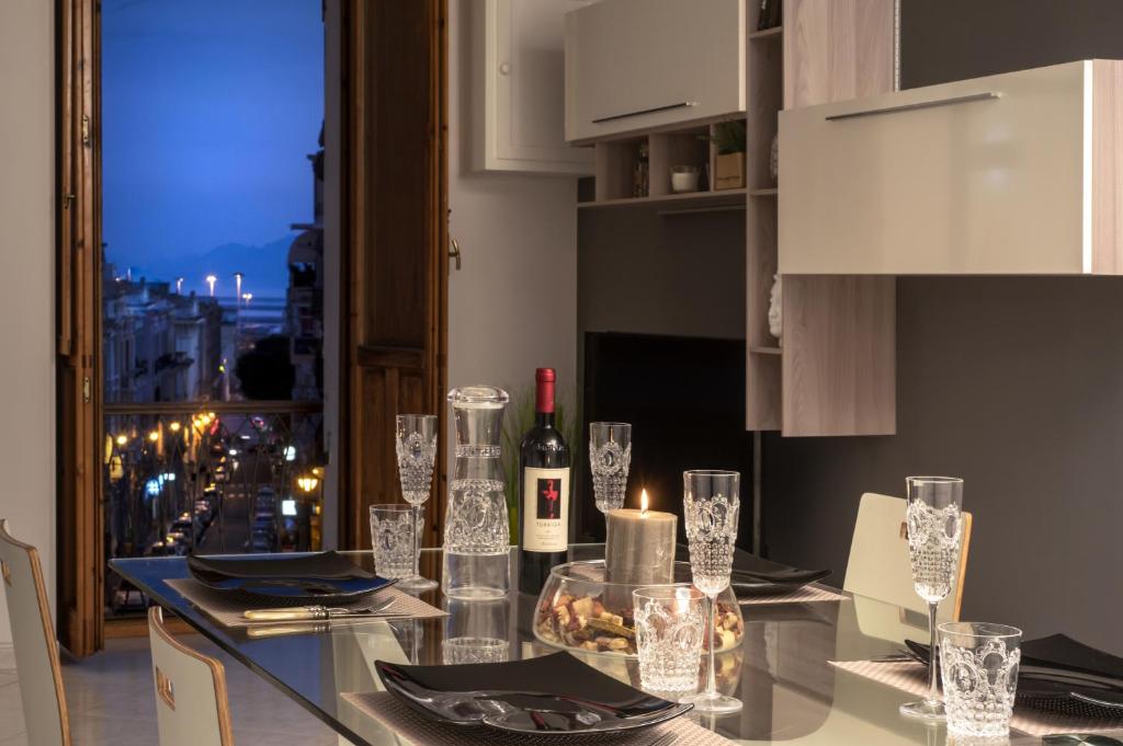 una cocina con una mesa de cristal con botellas de vino y copas en La Casa nel Corso en Cagliari