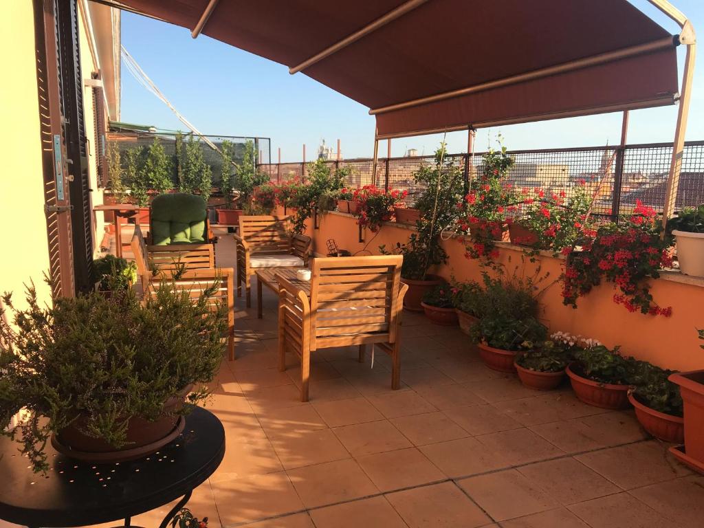 un patio con tavoli, sedie e piante in vaso di La Terrazza di Evelina Guest House a Roma