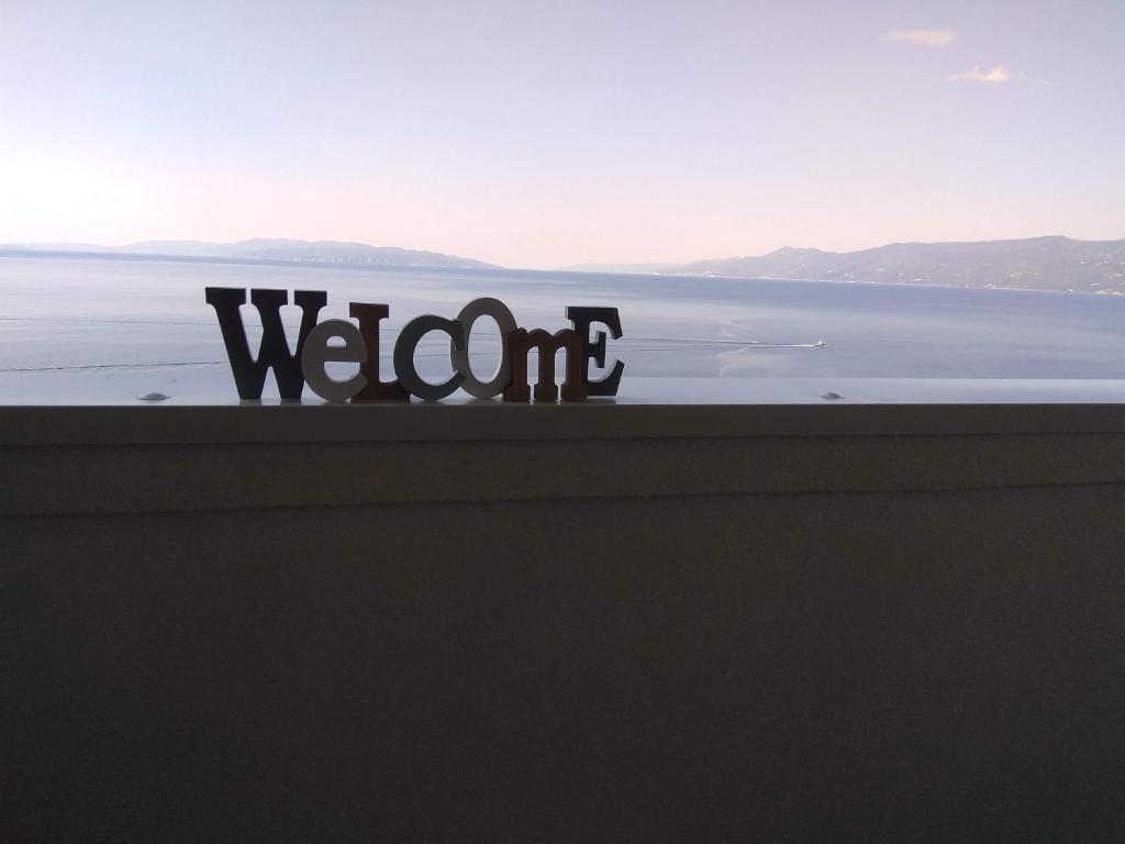 una vista del océano con el letrero en una cornisa en Seafoam Apartment, en Rijeka