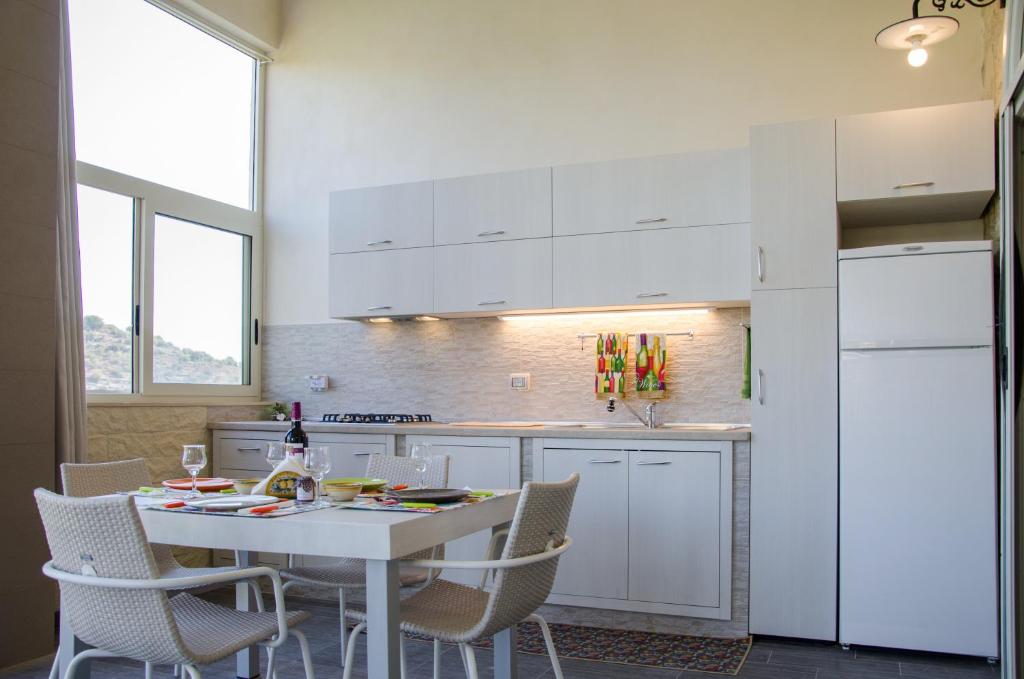 ラグーザにあるB&B Vista Ibleaのキッチン(白いテーブル、椅子、白い冷蔵庫付)