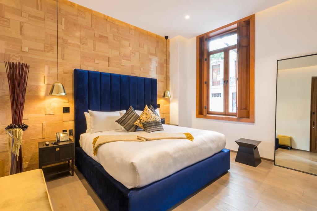 a bed with a blue headboard in a room at Casa Prim Hotel Boutique in Mexico City