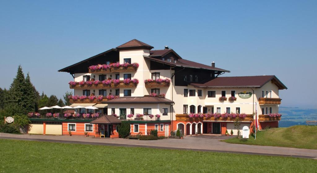 ein großes weißes Gebäude auf einem Hügel mit Blumen in der Unterkunft Hotel-Restaurant am Hochfuchs in Eugendorf