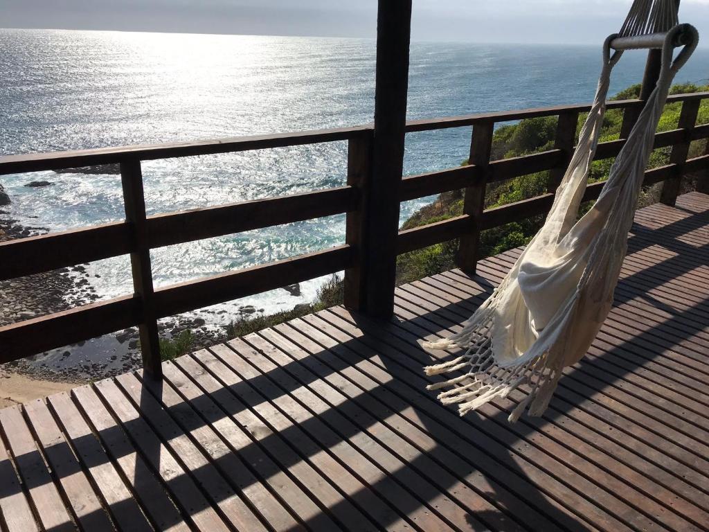 uma rede de descanso branca sentada numa varanda com vista para o oceano em Tunquen Magico em Tunquen