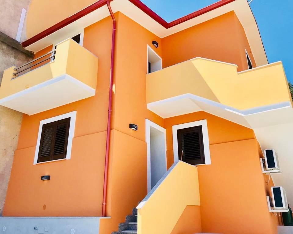 un edificio naranja con escaleras delante en Le case di Loris, en SantʼAntìoco