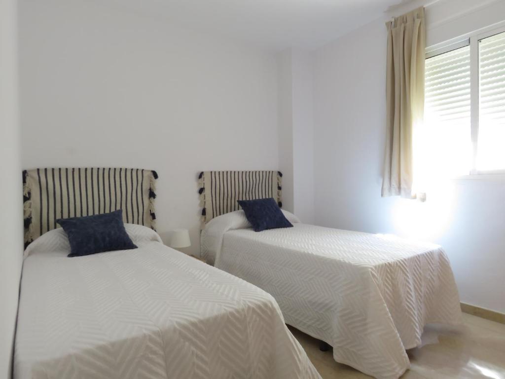 sypialnia z 2 łóżkami z białą pościelą i oknem w obiekcie Atico Torremolinos w mieście Torremolinos