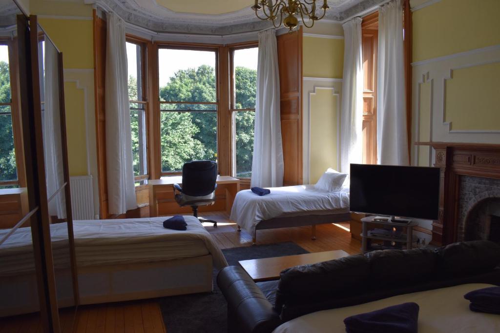 a living room with two beds and a television at Ardgowan Guest House in Edinburgh