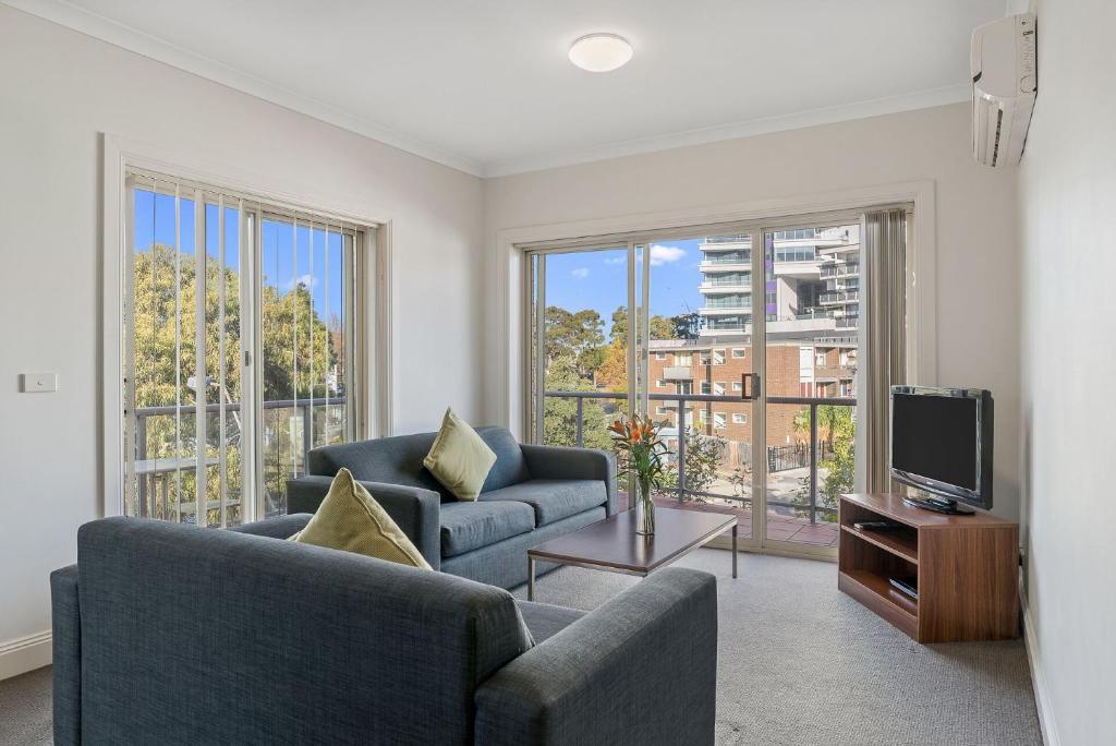uma sala de estar com dois sofás e uma televisão em Amazing Accommodations: St Kilda em Melbourne