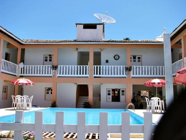 uma piscina em frente a uma casa com cadeiras e guarda-sóis em Pousada Asa Branca em Mangue Seco
