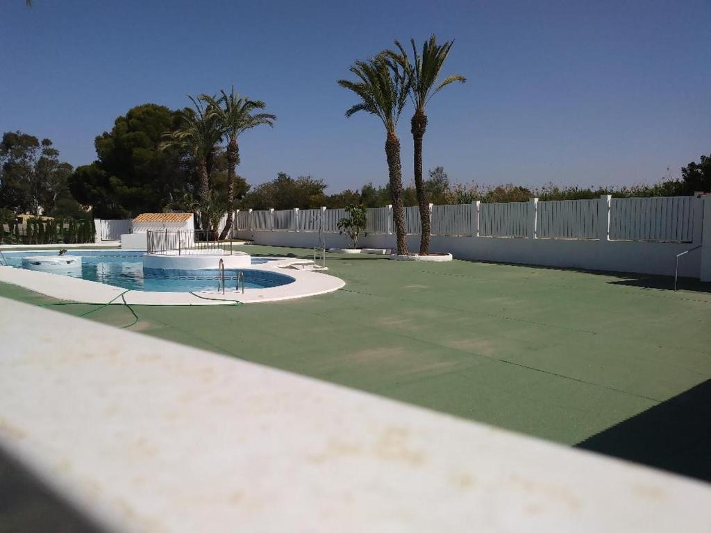 ベラにあるDuplex en Vera, Almeríaのテニスコート(プール、フェンス、ヤシの木あり)