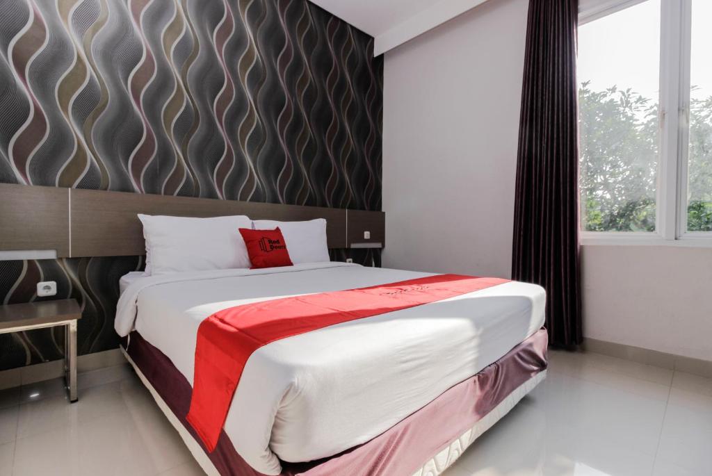 a bedroom with a large bed and a large window at RedDoorz near Goa Sunyaragi in Cirebon