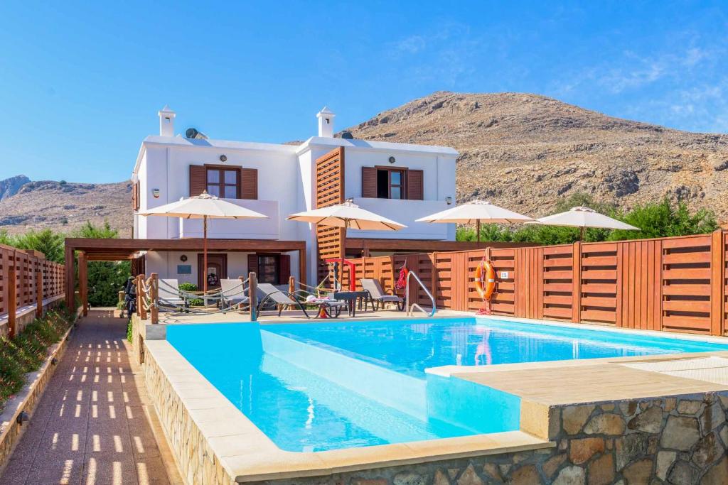 a villa with a swimming pool in front of a house at Lindos Ruby in Líndos