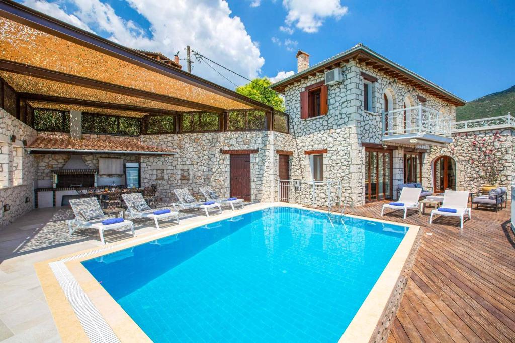 a swimming pool in front of a stone house at Villa Rachi in Vathí