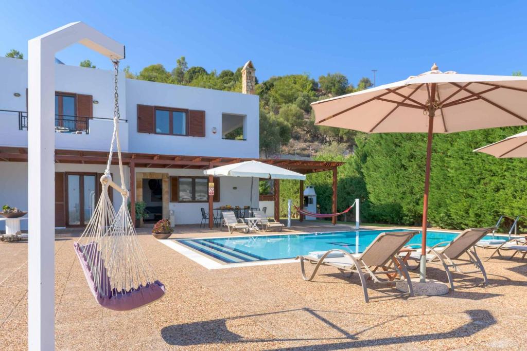 a villa with a swimming pool and two chairs and an umbrella at Villa Krini Eleni in vlicha