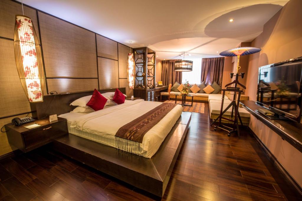 a bedroom with a large bed and a living room at Rose Garden Hotel in Yangon