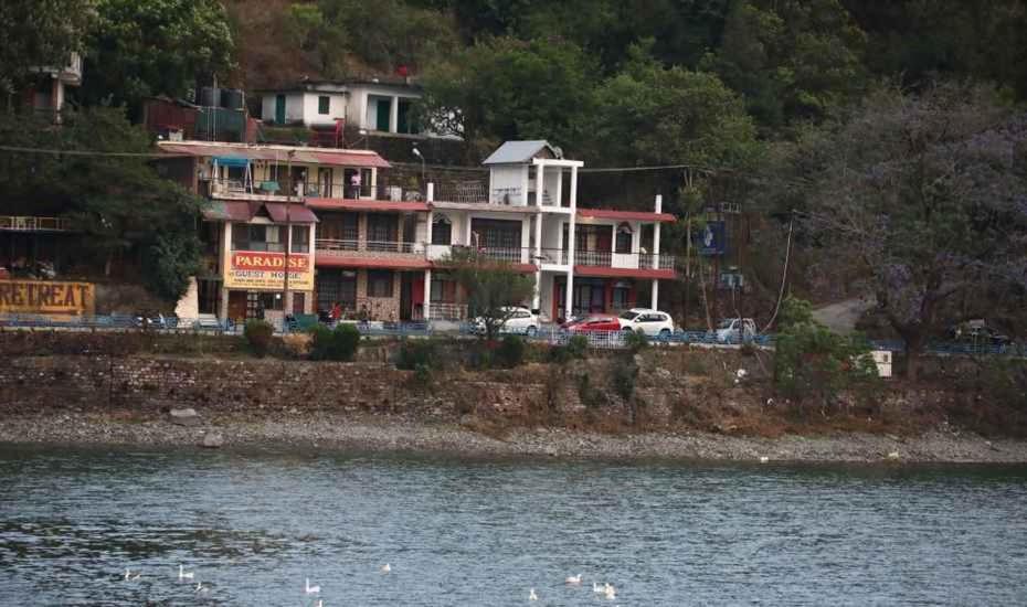 een groot huis op een heuvel naast een waterlichaam bij Jheel Facing rooms in Bhimtal in Bhīm Tāl