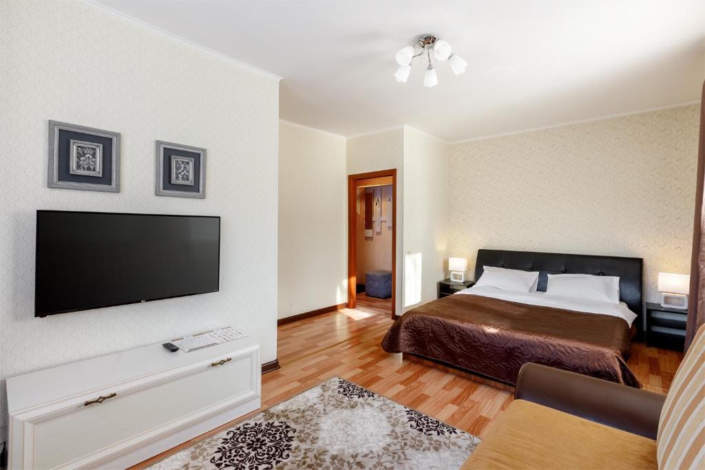 a bedroom with a bed and a flat screen tv at Апартаменты Авион Комфорт in Kemerovo