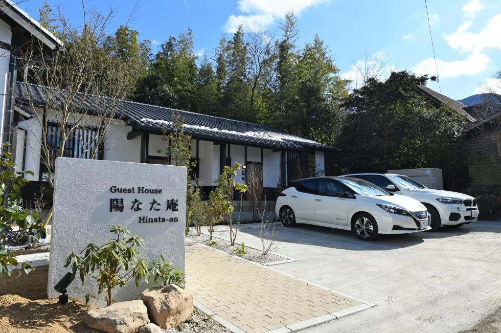 Deux voitures blanches garées devant une maison dans l'établissement Hinata-an, à Yufu