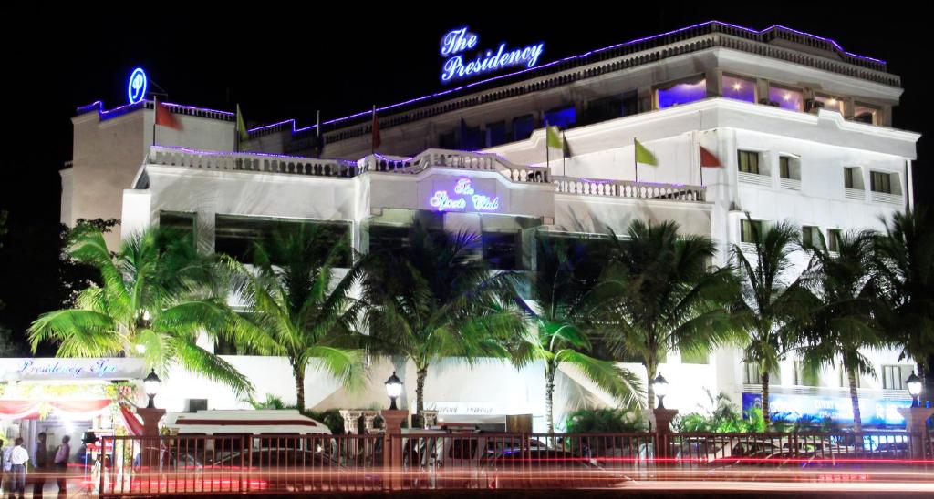 um hotel à noite com palmeiras em frente em The Presidency em Bhubaneshwar