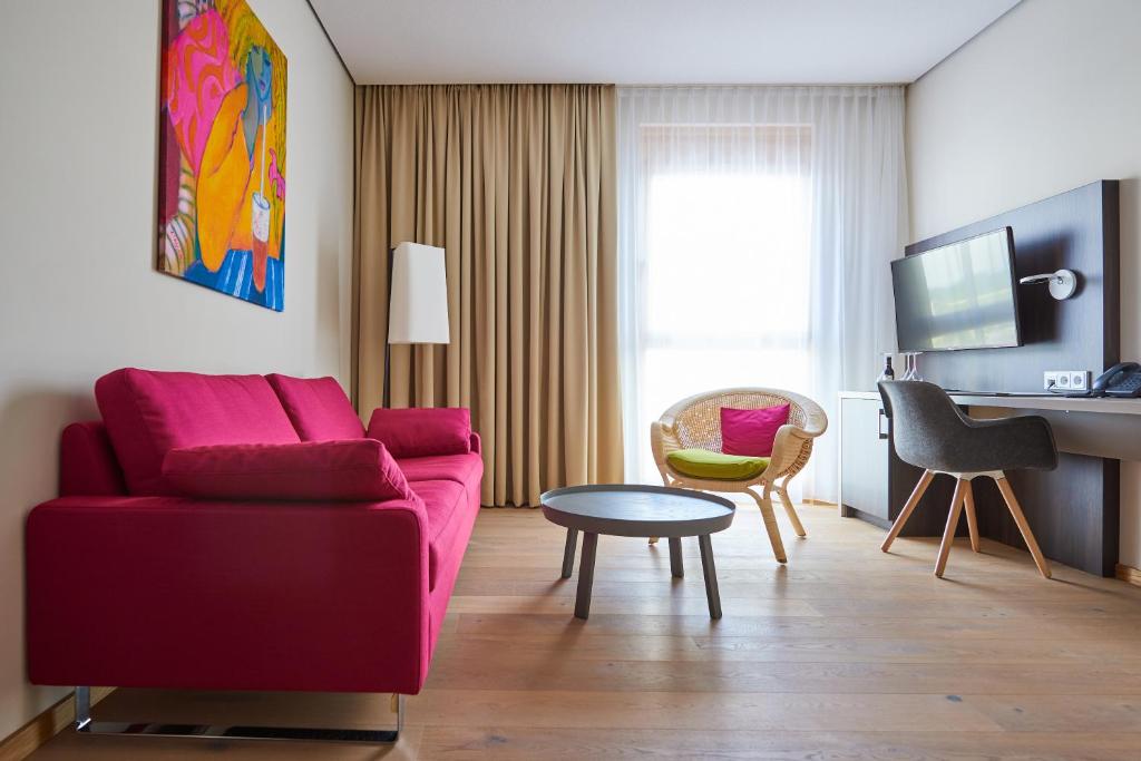 a living room with a red couch and a table at Hotel Calamus in Kehl am Rhein