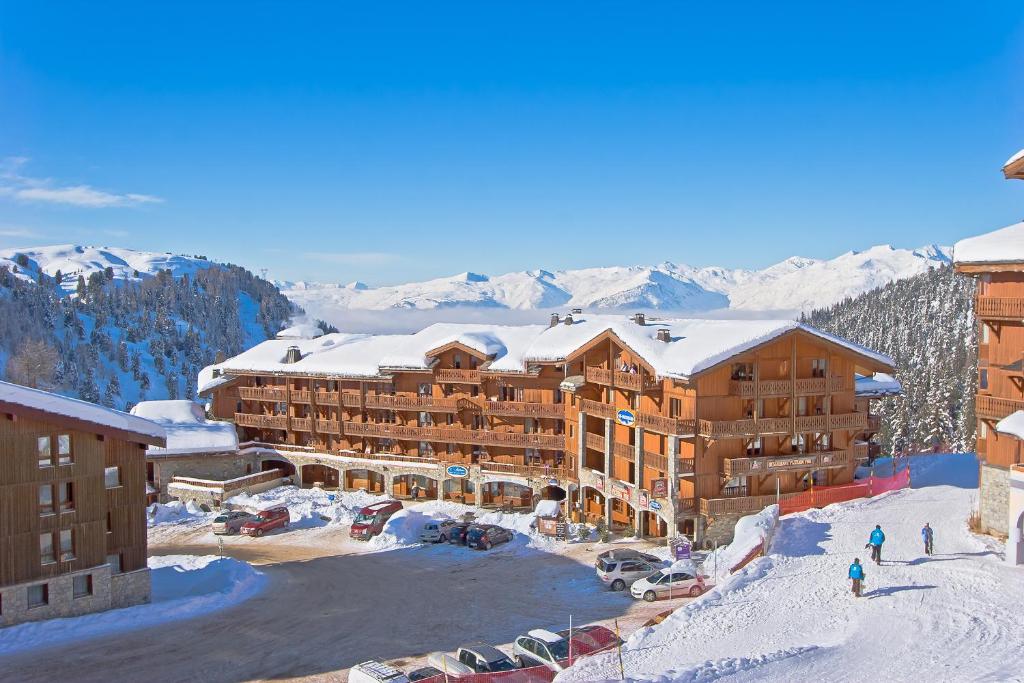 a ski lodge with snow covered mountains in the background at Résidence Les Balcons de Belle Plagne in Belle Plagne