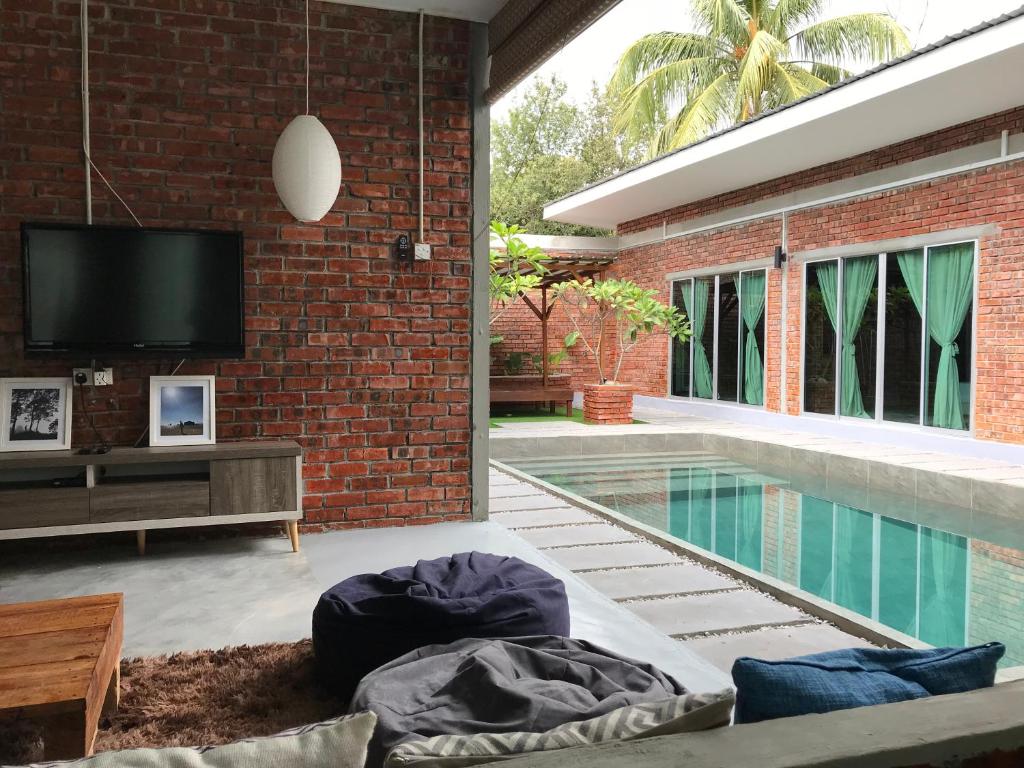 a living room with a tv and a swimming pool at Tanjung Rhu Pool Villa @ TRV in Huma