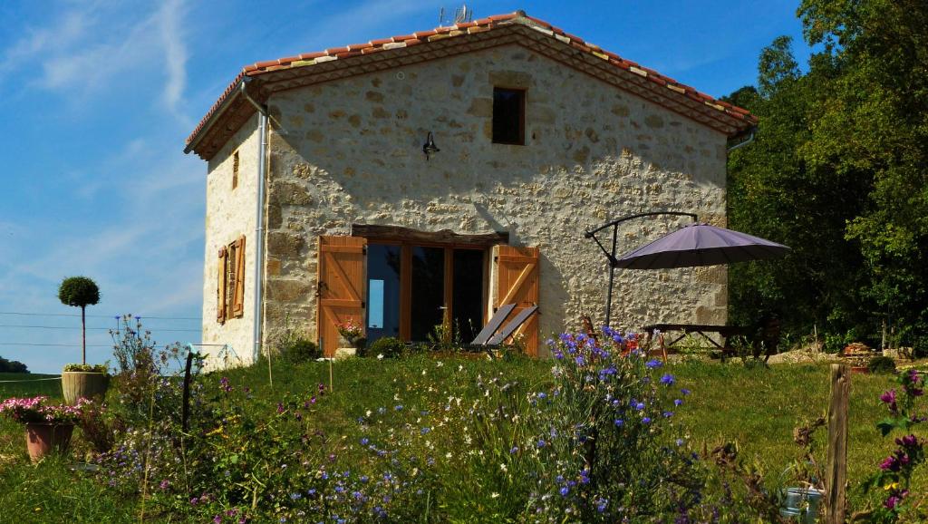 une maison en pierre avec une porte ouverte dans un champ dans l'établissement Laspeyreres, à Condom