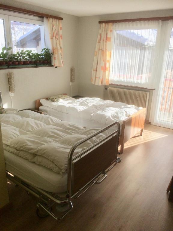 two beds in a room with two windows at B&B Haus Granit Saas Grund in Saas-Grund