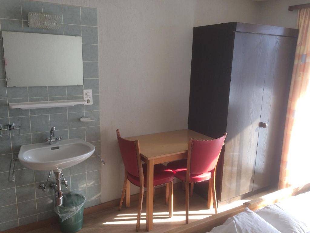 a bathroom with a table and two chairs and a sink at B&B Haus Granit Saas Grund in Saas-Grund