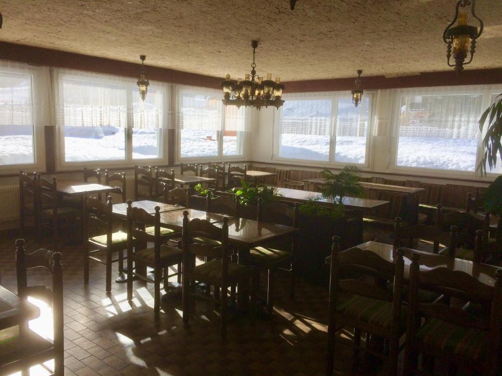 a dining room with tables and chairs and windows at B&B Haus Granit Saas Grund in Saas-Grund