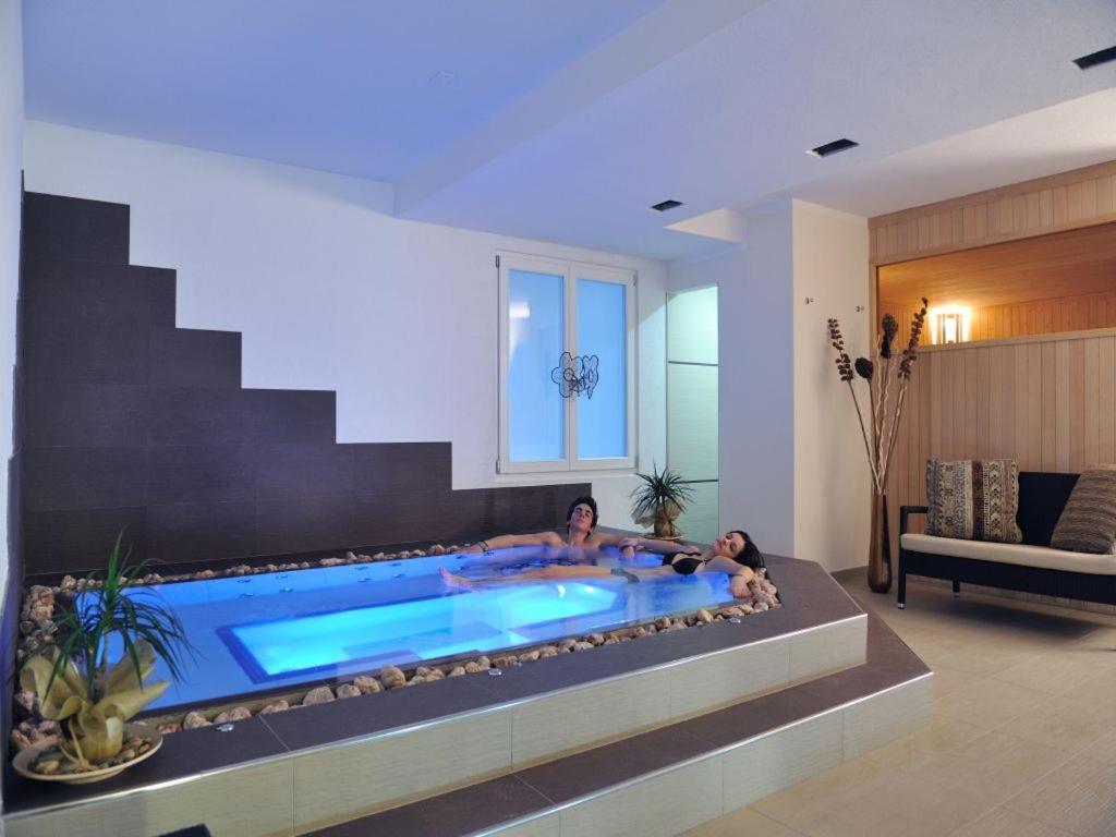 2 persone sedute in una piscina in un soggiorno di Bio Hotel Benny a Commezzadura