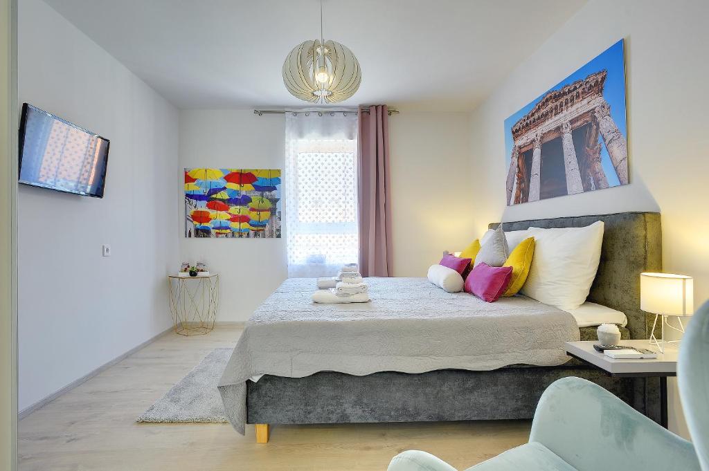 a bedroom with a king sized bed with colorful pillows at D&A Amphitheatre Apartments with free parking in Pula