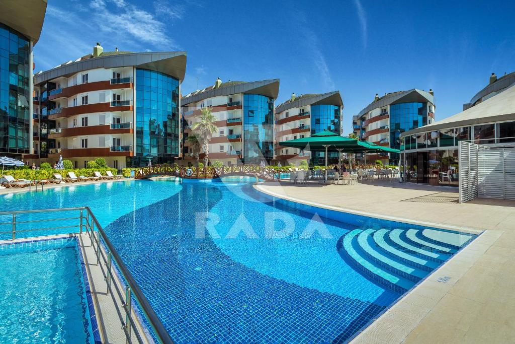 アンタルヤにあるOnkel Rada Apart Hotelの一部の建物の前に大きなスイミングプールがあります。