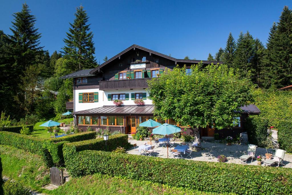 ein großes Haus mit einem Hof mit Stühlen und Sonnenschirmen in der Unterkunft Rostalm in Berchtesgaden