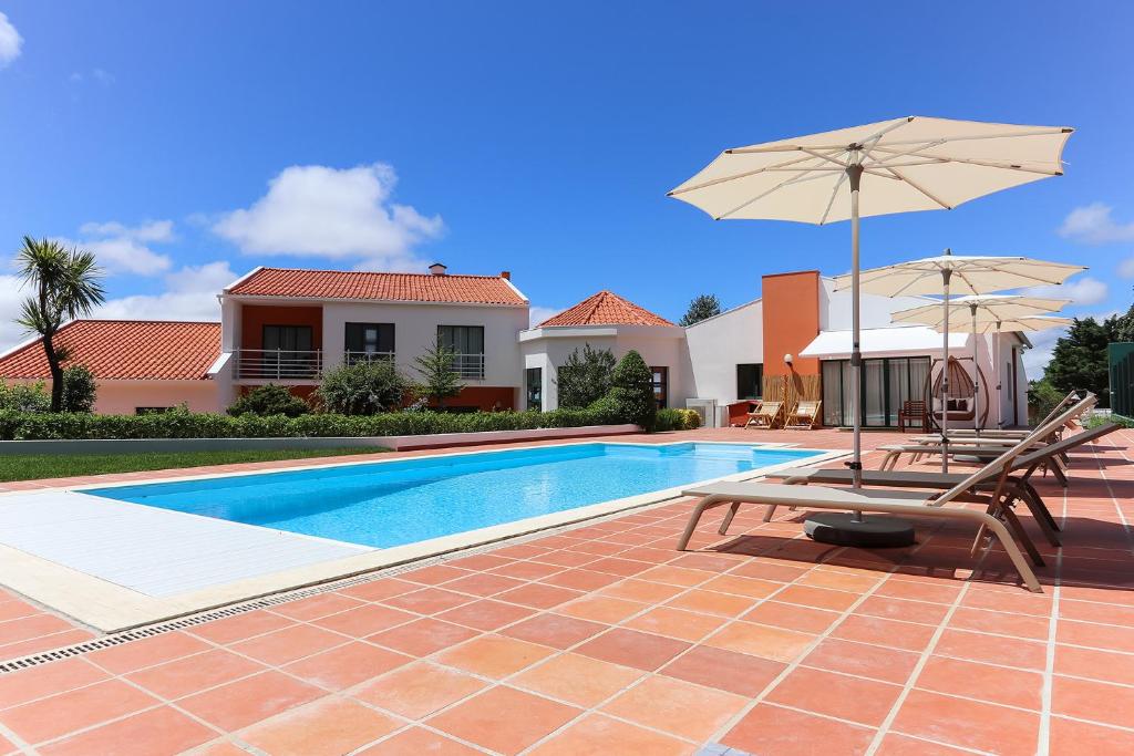 una piscina con due sedie e un ombrellone di Sintra Rural Home - Cerrado da Serra a Sintra