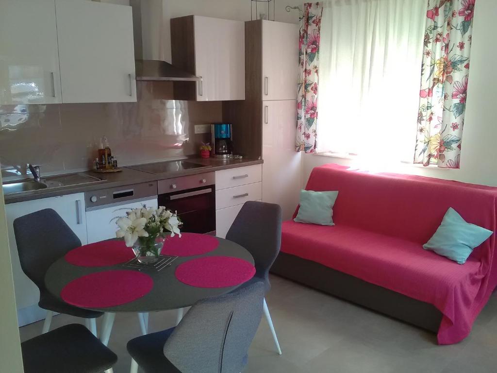 eine kleine Küche mit einem Tisch und einem rosa Sofa in der Unterkunft Podvršina1A Rosa in Preko