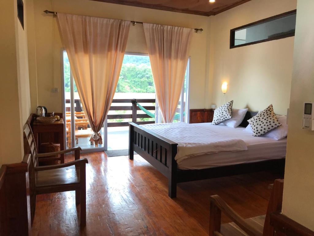 a bedroom with a bed and a balcony at Riverview Bungalows & GH in Muang Ngoy